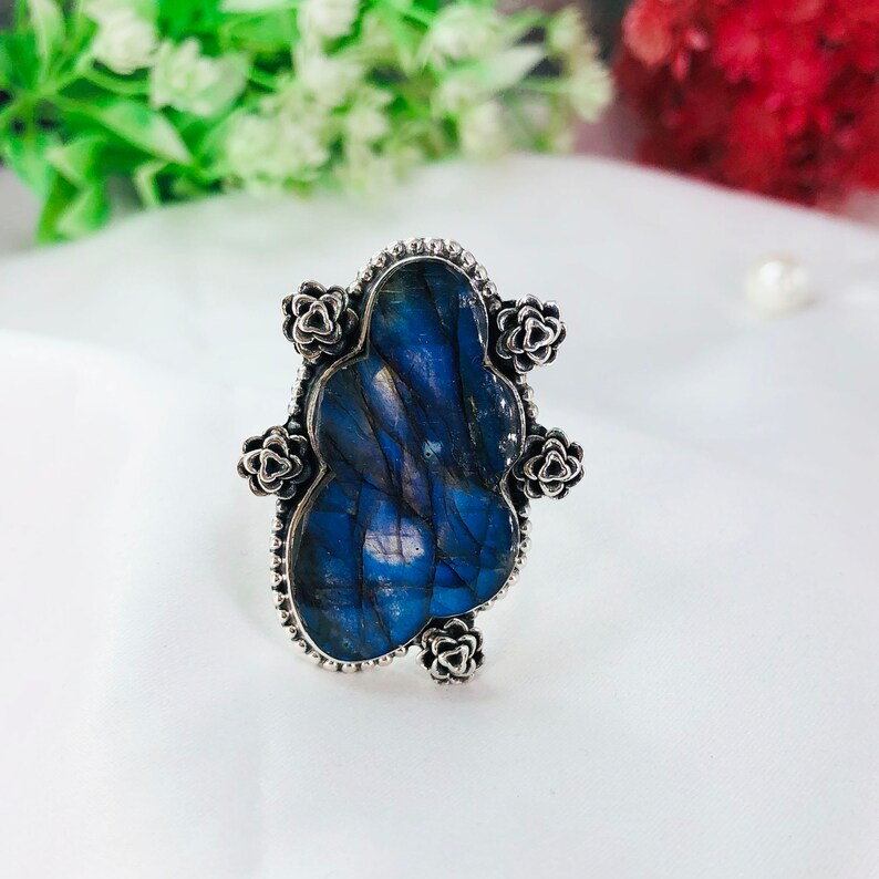 May include: A silver ring with a blue labradorite gemstone set in a floral design.