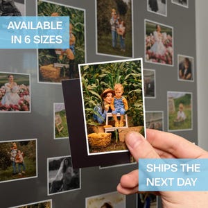 May include: A hand holds a framed photograph with a family portrait. The photo is surrounded by other framed photos of various sizes, attached to a grey surface. Text on the image reads "AVAILABLE IN 6 SIZES".