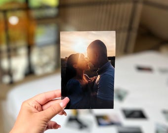 Op de afbeelding: Een rechthoekige fotoafdruk met het silhouet van twee mensen die tegenover elkaar staan tijdens een zonsondergang. Het warme gouden licht verlicht de randen van hun profielen tegen een donkere achtergrond en legt een intiem moment vast.