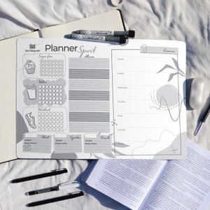 Könnte beinhalten: Ein graues Trockenlöschboard mit einem Planer zur Verfolgung von Fitnesszielen. Das Board hat Abschnitte zur Verfolgung der Wasseraufnahme, zuckerfreier Leckereien, Workouts und des Gewichts. Es enthält auch einen Wochenkalender und einen Abschnitt für Übungen. Das Board trägt die Aufschrift "Planner Sport" oben.