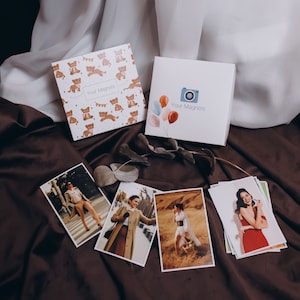 May include: Two boxes of magnets with the text "Your Magnets" on them. One box has a cartoon camera and balloons, the other has a pattern of cartoon animals. There are also several photographs of people in different poses.