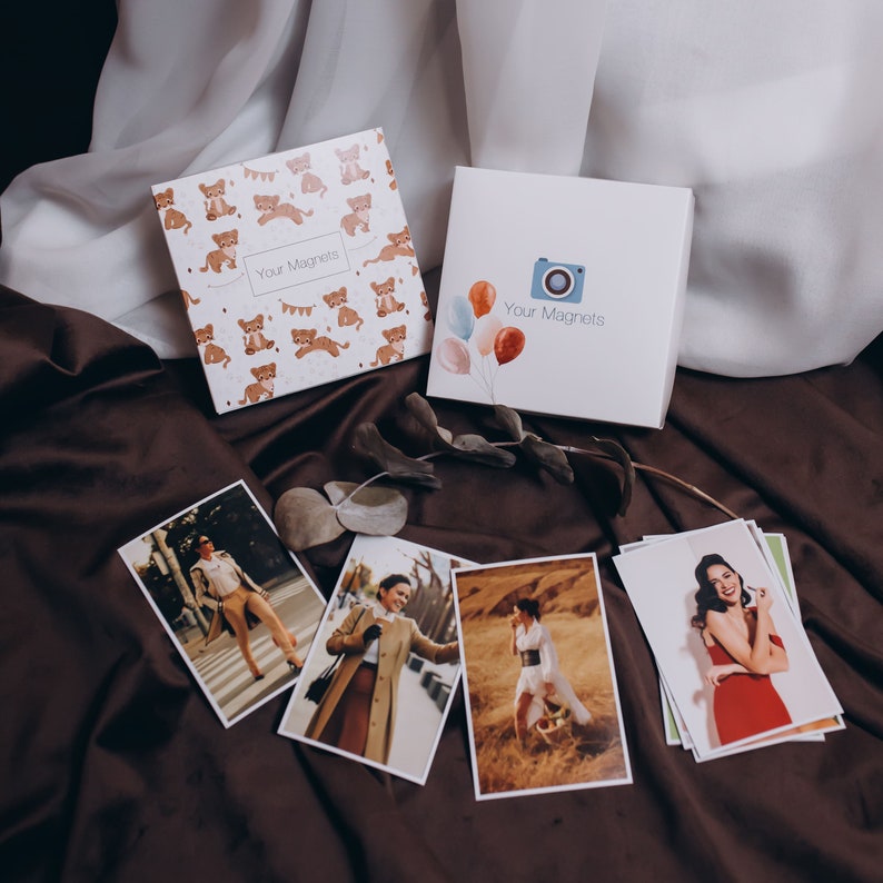 May include: Two boxes of magnets with the text "Your Magnets" on them. One box has a cartoon camera and balloons, the other has a pattern of cartoon animals. There are also several photographs of people in different poses.