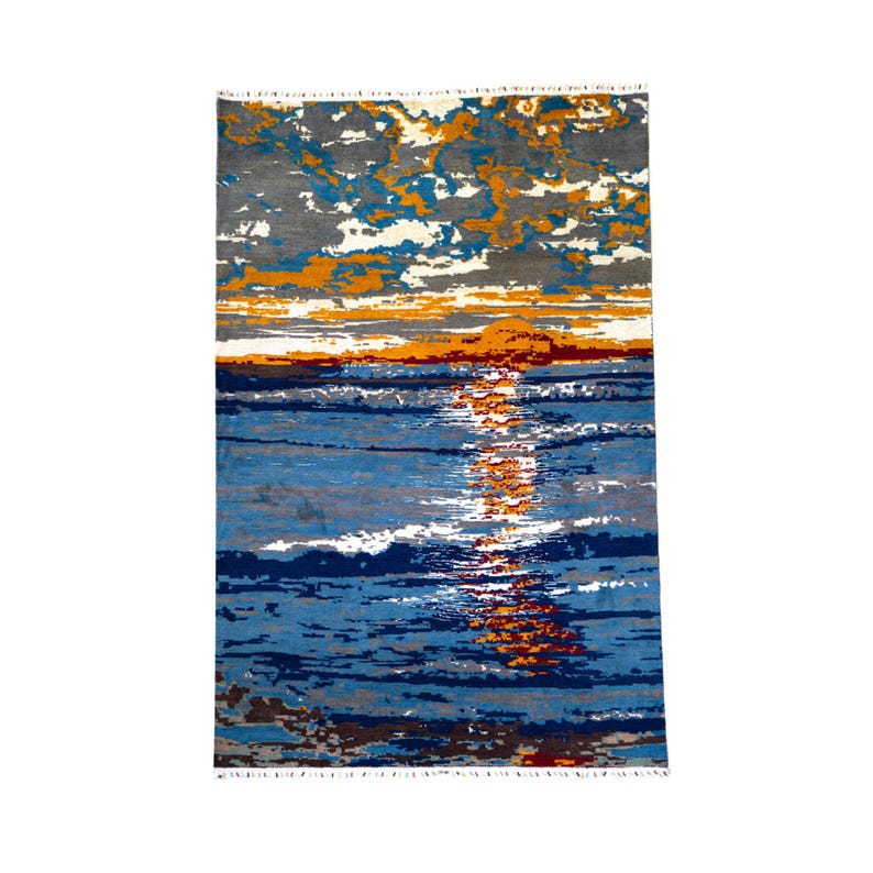 May include: Rectangular rug with a sunset design. The rug features a blue and white ocean with a bright orange and yellow sunset. The top portion of the rug has a gray, blue, and white cloud design. The rug has a fringe on the top and bottom edges.