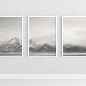 May include: Three black and white framed photographs of mountains with fog in the background.