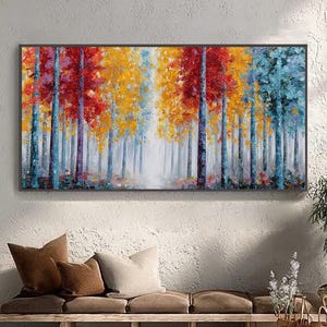 May include: A rectangular framed painting depicts a colorful forest scene. The artwork features trees with red, yellow, and blue foliage. The painting is displayed above a wooden bench with pillows, next to a potted plant and a woven basket.