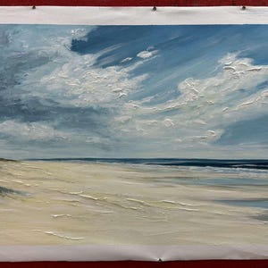 May include: A painting of a seascape with a sandy beach and blue sky with white clouds. The ocean is a deep blue and the sand is a light beige. The painting is done in a realistic style.