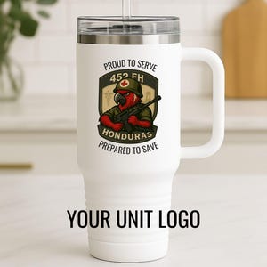 Può includere: Tazza da viaggio bianca con manico e coperchio nero. La tazza presenta un emblema a tema militare con un pappagallo con un elmetto e un fucile, con il testo "Proud to Serve 452 FH Honduras Prepared to Save". Il fondo della tazza recita "YOUR UNIT LOGO".