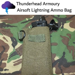 May include: A green canvas ammo bag with a black strap and a black plastic magazine pouch attached. The bag is labeled "Thunderhead Armoury Airsoft Lightning Ammo Bag".