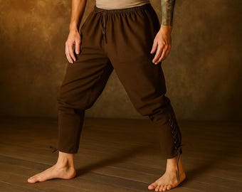 May include: Brown medieval-style pants with a drawstring waist and laced details on the lower legs. The pants are made of a soft fabric and are suitable for historical reenactments or costume events.