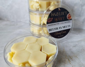 Może przedstawiać: Przezroczysty pojemnik wypełniony sześciokątnymi woskowymi topionymi woskami o zapachu miodu i kakao. Pojemnik jest oznaczony etykietą "Hazelnut & Honey Beeswax Melts Honey Cocoa".