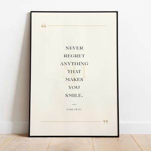 May include: Framed art print with the quote "Never regret anything that makes you smile." The text is in a serif font, centered on a cream-colored background, and framed in black. The quote is attributed to Mark Twain.