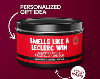 May include: A black and red candle tin with the text "Smells Like A Leclerc Win" and "Mark's Lucky Race Day Candle". The text "Winning Sure Smells Good" is printed in smaller font below. The text "Your Name" is printed on a white circle below the tin.
