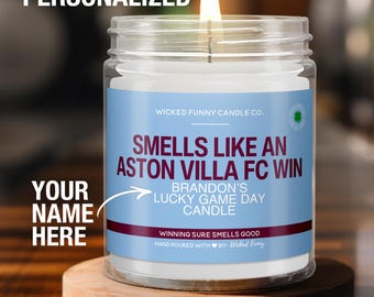 May include: A white candle in a clear glass jar with a blue and white label that reads "Smells Like An Aston Villa FC Win" and "Brandon's Lucky Game Day Candle". The label also includes the text "Winning Sure Smells Good" and "Hand Poured With by: Wicked Funny".