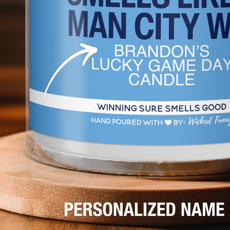 Puede incluir: Una vela azul y blanca con el texto "Brandon's Lucky Game Day Candle" y "Winning Sure Smells Good". La vela est&aacute; hecha a mano con un s&iacute;mbolo de coraz&oacute;n y el texto "By: Wicked Funny".