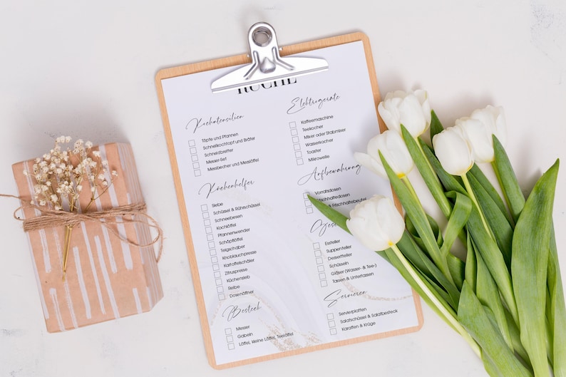 Puede incluir: Una lista de verificaci&oacute;n en un portapapeles con el t&iacute;tulo "Hochzeit" (Boda) en alem&aacute;n. La lista de verificaci&oacute;n incluye categor&iacute;as para "Vorbereitung" (Preparaci&oacute;n), "Kochhilfe" (Ayuda para cocinar), "Getr&auml;nke" (Bebidas), "Essen" (Comida), "Dekoration" (Decoraci&oacute;n), "Sitzordnung" (Organizaci&oacute;n de asientos), "Ankleidung" (Vestimenta), "Anfahrt" (Instrucciones de viaje), "Sonstiges" (Otros). Un ramo de tulipanes blancos se encuentra en la esquina inferior derecha de la imagen.