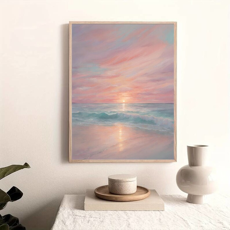 Puede incluir: Una pintura enmarcada de un paisaje mar&iacute;timo con una puesta de sol rosa y naranja sobre el oc&eacute;ano. El agua es de color azul claro y la arena es blanca.