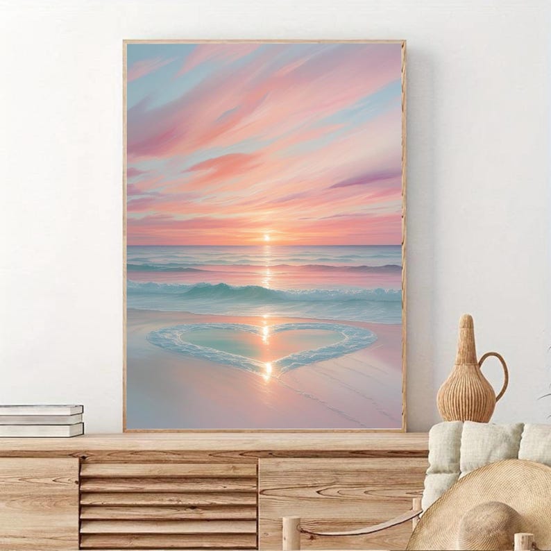 May include: A painting of a pink and blue sunset over a beach with a heart shape formed by the waves in the sand.