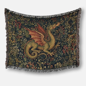 May include: A woven throw blanket featuring a central green dragon with red wings breathing fire, set against a dark background filled with a dense pattern of colorful wildflowers and foliage, finished with decorative fringe along all four edges.