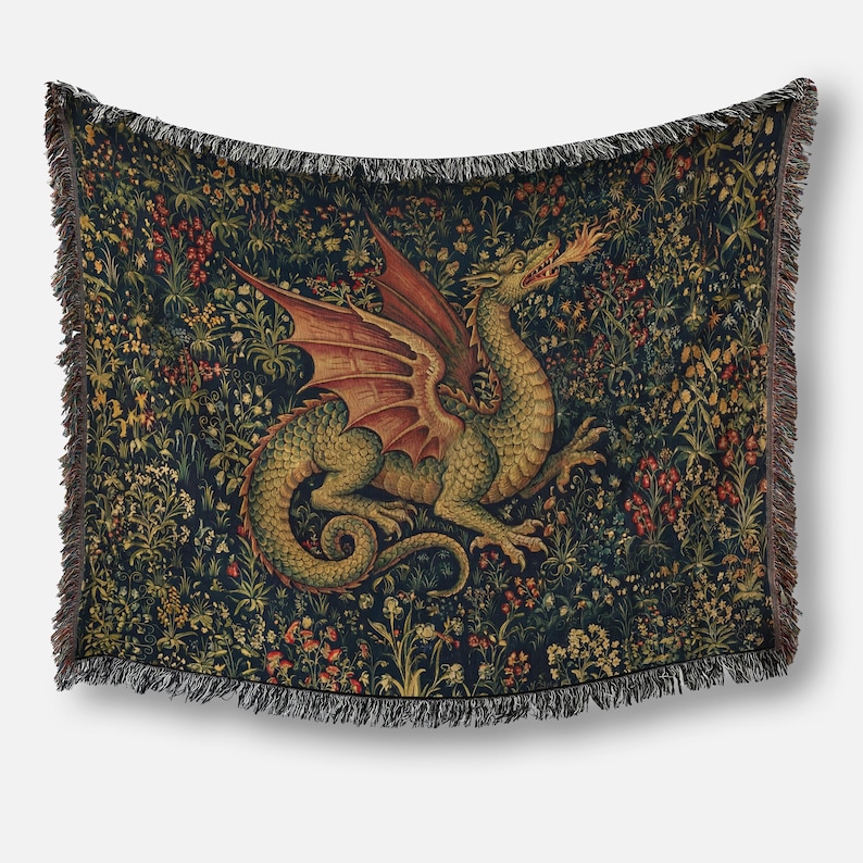 May include: A woven throw blanket featuring a central green dragon with red wings breathing fire, set against a dark background filled with a dense pattern of colorful wildflowers and foliage, finished with decorative fringe along all four edges.