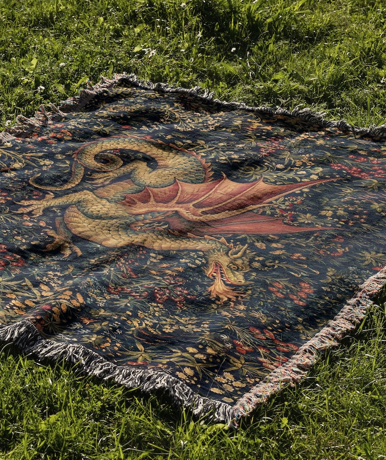 May include: A rectangular woven throw blanket featuring a dark navy blue background with a detailed illustration of a golden dragon with red wings breathing fire, surrounded by a dense pattern of colorful flowers, foliage, and fringed edges.