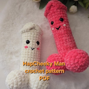 May include: Two phallic-shaped plush toys made of soft, textured yarn. One is white and the other is bright pink. Both feature black plastic safety eyes, embroidered smiles, and pink stitched cheeks. Text reads: HapCheeky Man crochet pattern PDF.