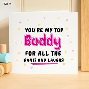 Peut inclure: Carte de vœux blanche avec le texte "YOU'RE MY TOP Buddy FOR ALL THE RANTS AND LAUGHS !" en noir et rose. La carte est décorée d'étoiles jaunes et de cœurs roses.