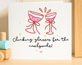 May include: A white greeting card featuring a red line drawing of two clinking wine glasses with pink liquid, surrounded by yellow stars and a small pink heart. The text reads: Clinking glasses for the newlyweds!