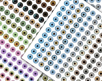 Puede incluir: Surtido de ojos de muñeca de plástico de colores en varios tamaños y colores, incluyendo azul, verde, marrón y morado. Los ojos están dispuestos en filas sobre un fondo blanco.