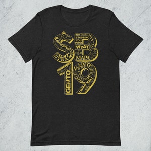 May include: A black t-shirt with a gold graphic design featuring the number 19 and various words and phrases, including "What?", "Freedom", "Gento", "I Want You", "No Ikako", "Stopping You", "Mana", "Wyatt", "Mapa", "SLM", "Iham", "Bazinga", "Hanggang Sa Huli", and "Grimzone".