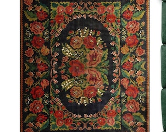 May include: A vintage floral rug with a dark blue background and a central design of red, pink, and white flowers. The rug has a border of green leaves and flowers.