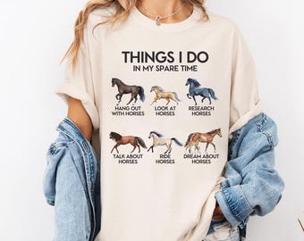 Könnte beinhalten: Cremefarbenes T-Shirt mit dem Text "THINGS I DO IN MY SPARE TIME" und Pferdeillustrationen. Das Shirt listet Aktivitäten wie "Hang Out With Horses" und "Dream About Horses" auf.