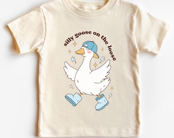 May include: A cream-coloured t-shirt with a cartoon goose wearing a blue cap and boots, and the text "silly goose on the loose". The goose is shown walking with wings spread, surrounded by lightning bolts and stars.