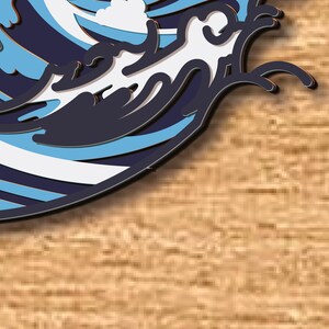 May include: A blue and white paper cut-out of a wave crashing on a wooden surface.