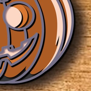 May include: A layered, orange pumpkin design with a carved face, featuring a black shadow and a light beige interior. The pumpkin is set against a wooden background, creating a Halloween theme.