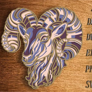 Może przedstawiać: Szczegółowa ilustracja głowy barana z misternymi, warstwowymi rogami w odcieniach brązu, różu i fioletu. Twarz barana jest przedstawiona w realistycznym stylu z skupionym wyrazem twarzy.