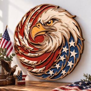 May include: A circular layered wooden wall art piece featuring a stylized bald eagle head. The design incorporates red, white, and blue colors with star cutouts on the right side, mimicking the American flag pattern with intricate wood grain.