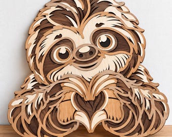 May include: A multi-layered wooden wall art piece depicting a sloth with a light and dark brown finish. The sloth is shown with its arms positioned in front of its chest to form a heart shape, featuring intricate cutouts and stacked wood layers.