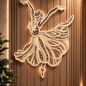 Op de afbeelding: Een gelaagd houten wandkunstwerk dat een ballerina in een dynamische danshouding weergeeft. Het ontwerp bevat ingewikkelde uitsparingen in de rok, wat een multidimensionaal effect creëert met warme achtergrondverlichting op het hout.