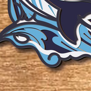 May include: A blue and white paper cut-out of a dolphin jumping out of the water. The dolphin is outlined in black and has a 3D effect.