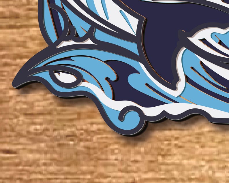 May include: A blue and white paper cut-out of a dolphin jumping out of the water. The dolphin is outlined in black and has a 3D effect.