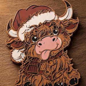 May include: A layered wooden wall art piece depicting a Highland cow with shaggy brown fur, wearing a red and white Santa hat and a plaid scarf. The cow has a pink snout, large dark eyes, and its tongue is sticking out, crafted with depth.