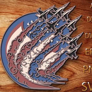 May include: A layered design featuring fighter jets soaring through the air, with a backdrop of the American flag. The jets are depicted in black and white, with trails of smoke in red, white, and blue. The design is set against a blue circle.