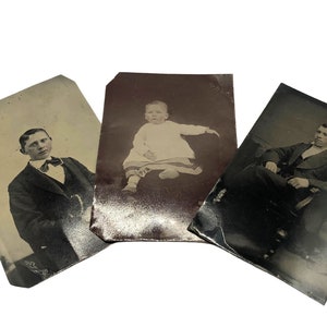 May include: Three antique black and white photographs. One shows a young man in a suit and bow tie, another a baby in a dress, and the third a man seated in a chair. The photos have aged edges.