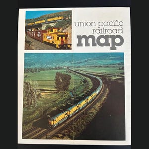 May include: A vintage Union Pacific Railroad map with two train scenes. The top shows a yellow train on a bridge, the bottom a long train through a green landscape. The map's title is in large grey letters. The map is a vintage item.
