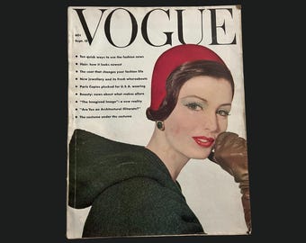 May include: A vintage Vogue magazine cover. The cover features a woman wearing a red hat and a dark green coat. The magazine's title, "VOGUE," is at the top. The cover includes text about fashion and beauty.