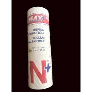 May include: A cylindrical roll of white thermal facsimile paper wrapped in clear plastic. The label features the text 'ROFAX PLUS', 'THERMAL FACSIMILE ROLL', and dimensions of 21.6 cm by 45 m, with a large red 'N' and blue plus sign.