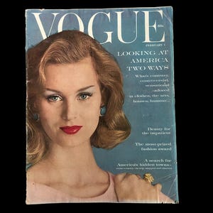 Può includere: Copertina della rivista Vogue del febbraio 1960. La copertina presenta una donna con rossetto rosso e un top rosa. Il titolo della rivista è in grandi lettere bianche, con il titolo "LOOKING AT AMERICA TWO WAYS."