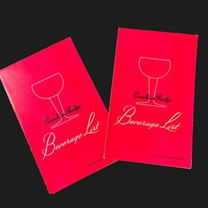Peut inclure: Deux livrets rouges vintage "Canadian Pacific Beverage List". Chaque livret présente une illustration de verre à vin blanc et le texte "Canadian Pacific Beverage List" en cursive. Le fond est noir.