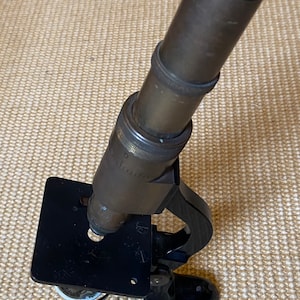 May include: A vintage brass microscope with a black base and a black handle. The microscope has a focusing knob and a stage for viewing specimens.