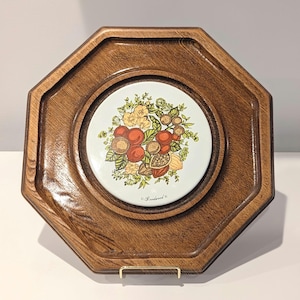 May include: An octagonal wooden serving tray with a central ceramic tile. The tile features a floral and fruit design in shades of red, yellow, and green. The tray has a dark wood finish and a raised edge.